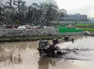 Traktor tanpa operator tampak berjalan sendiri di dekat areal pemakaman. Jangan buru-buru takut atau kabur, kendaraan tersebut merupakan bagian dari penerapan teknologi pertanian cerdas AI-TRAC yang dikendalikan dari jarak jauh. (Dok. Propetani)
